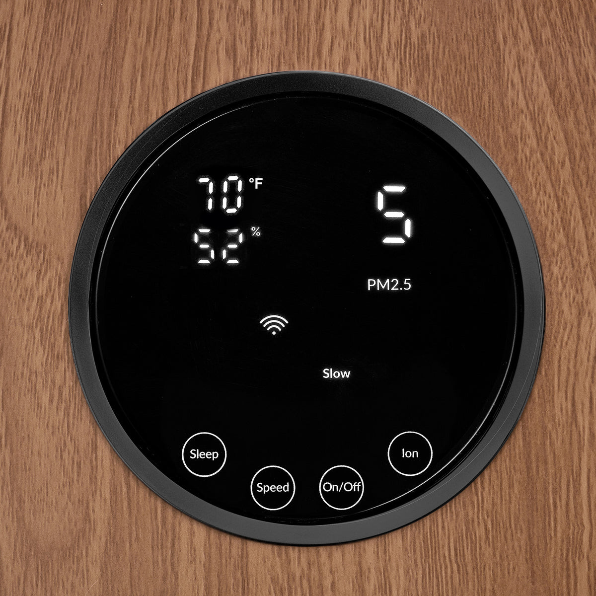 Close-up of the round touch display on the Klarta Forste air purifier in Wood Black, framed by the wood-grain front panel