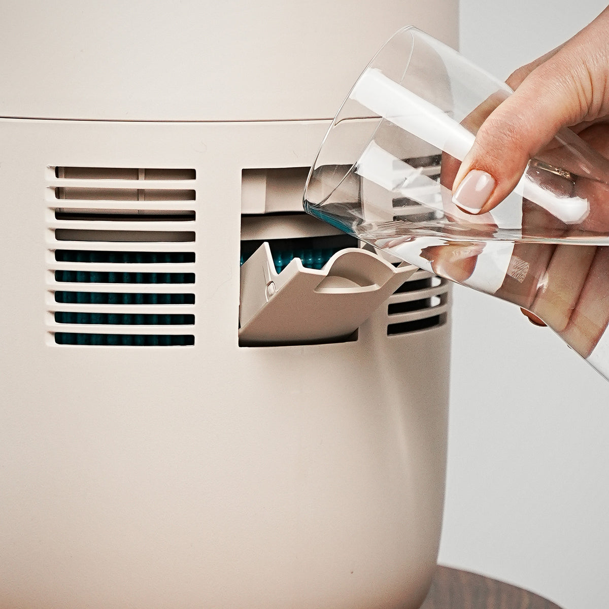 Water being poured into the front fill opening of the Klarta Humea evaporative humidifier in Beige