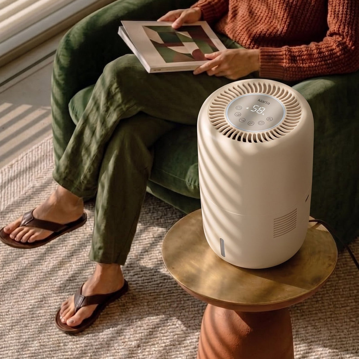 Klarta Humea humidifier in Beige on a side table beside a person reading in an armchair