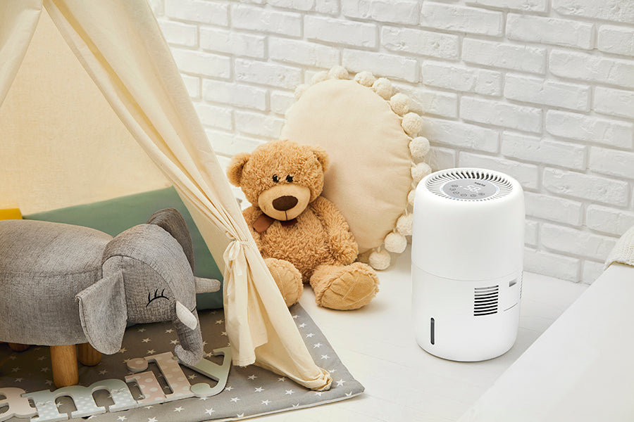 Klarta Humea evaporative humidifier in White on a nursery floor beside a play tent and a teddy bear