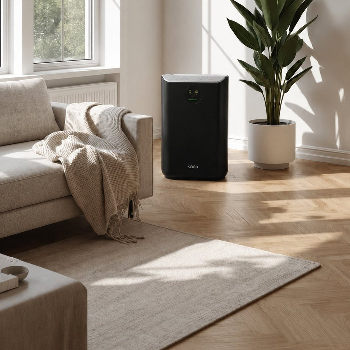 Klarta Stor air purifier in Full Black in a bright living room corner next to a plant