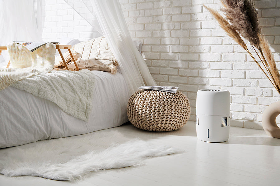 Klarta Humea evaporative humidifier in White in a bright bedroom next to a knitted pouf